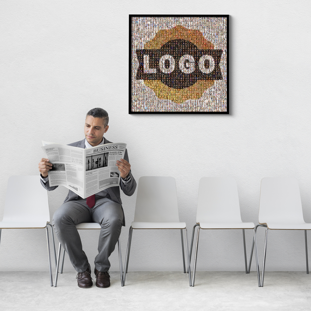 Schwarz gerahmtes Fotomosaik mit Firmenlogo aus Mitarbeiterfotos an der Wand über einer Stuhlreihe im Wartebereich